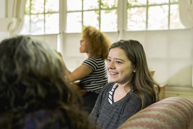 Smiling students are seated together in a residence hall lounge, laughing and talking